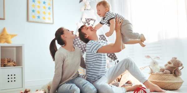 family mother father and baby son playing together in children's playroom